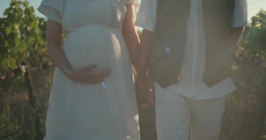 Man walking alongside his pregnant wife in a plantation environment
