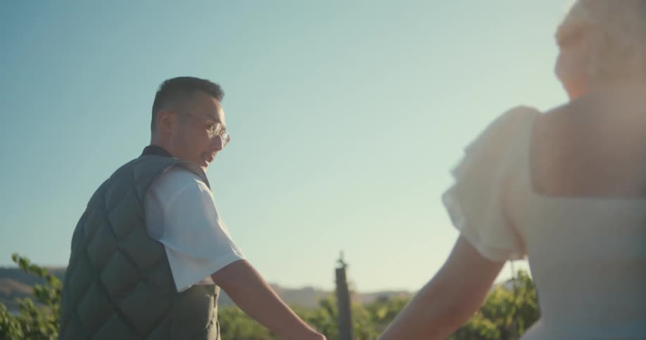 A man and a woman holding hands walking in a grass field