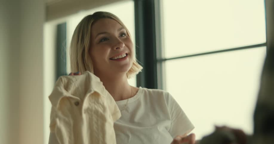 A man and woman are looking at baby clothes on their bed