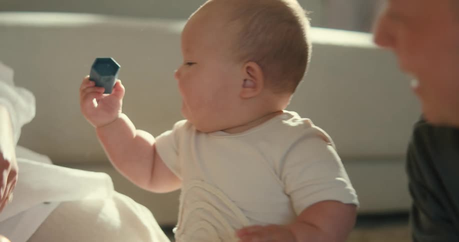 parent playing with their baby who is biting toys