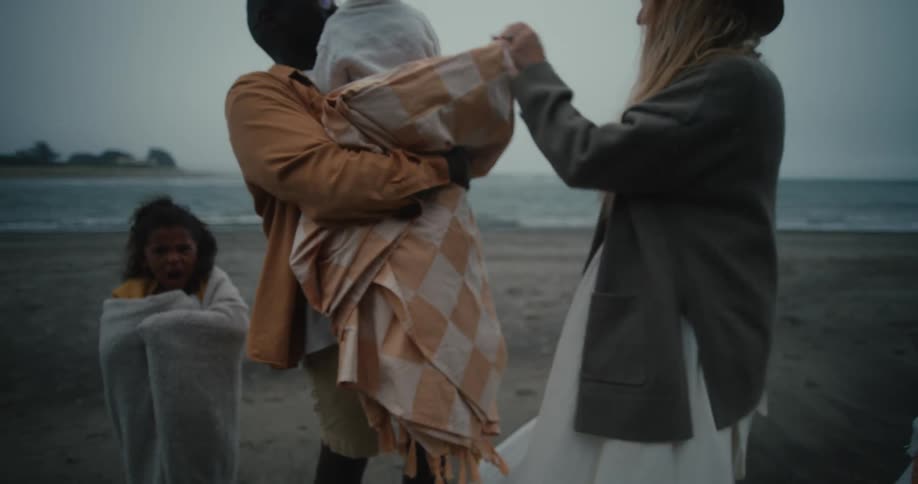 Family at the beach on a windy day with parents holding onto their children