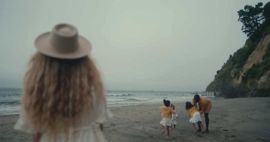 Father playing with his daughters on a beach while the mother watches