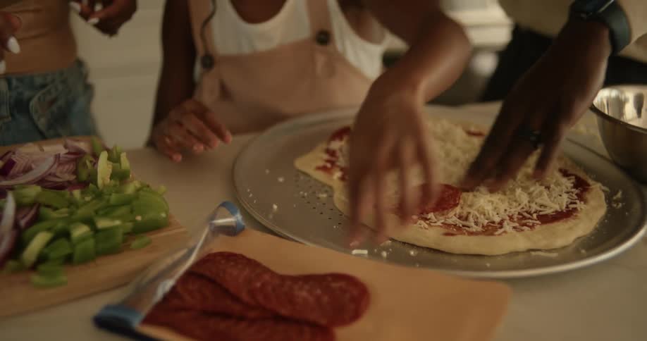 People are making a pizza in the kitchen