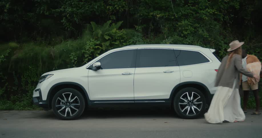 A black man a white woman and their three kids walking into a white suv while coming from a picnic