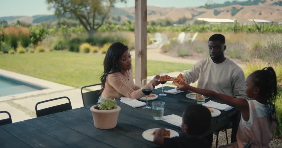 Parents sitting at the table with their children to eat pizza