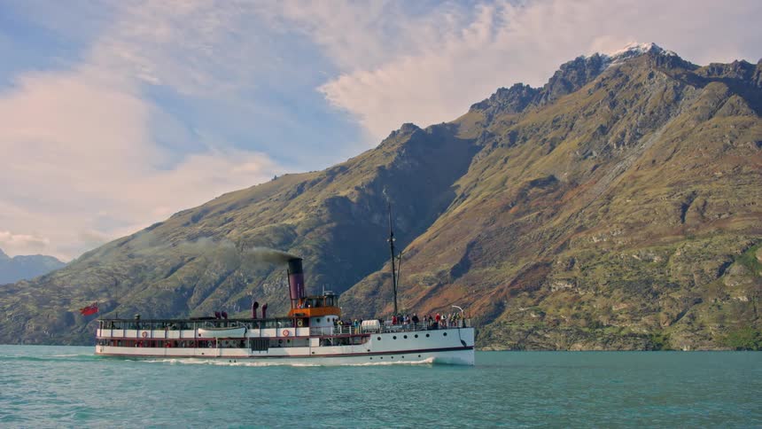 A long ship cruising on the lake near a mountain