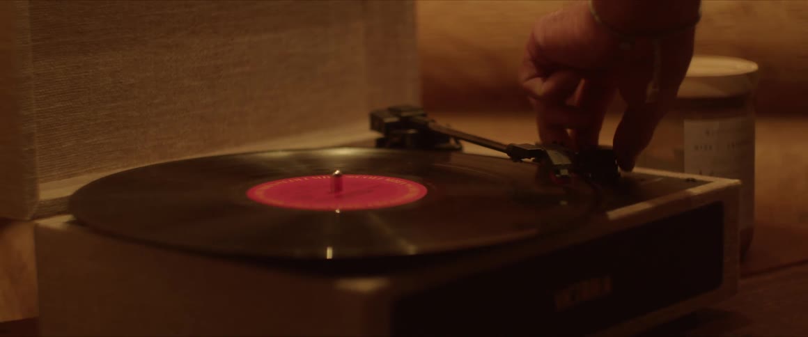 A person puts a record on the player and turns it on