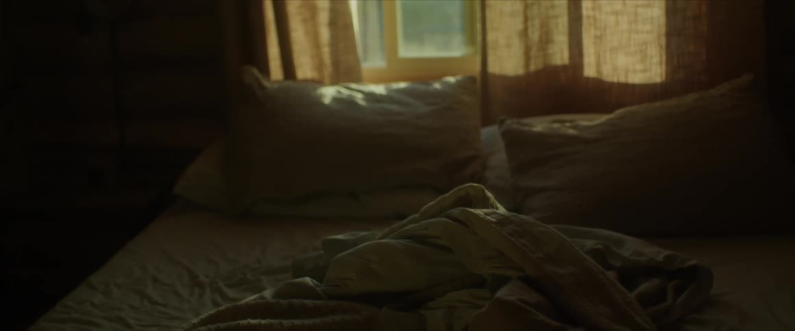 A bed in a dark room with a window