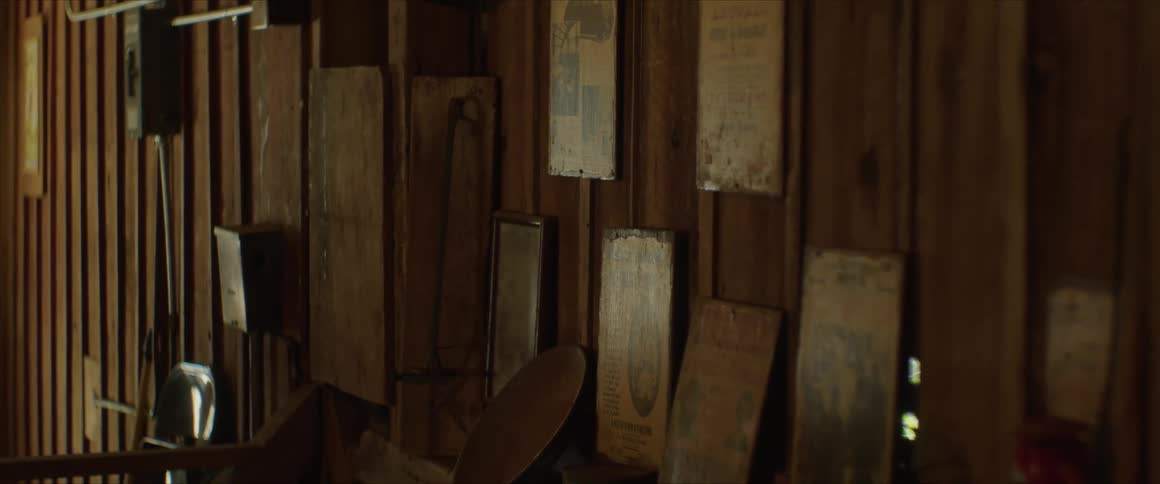 Several old paintings and portraits hang on a wooden wall