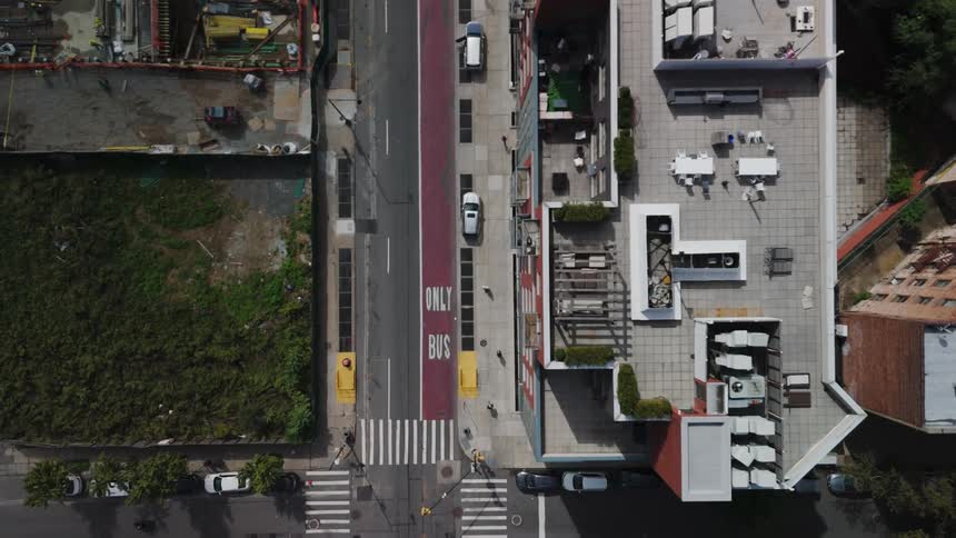 Aerial view of a suburban neighborhood with cars and a bus passing over the road during day time