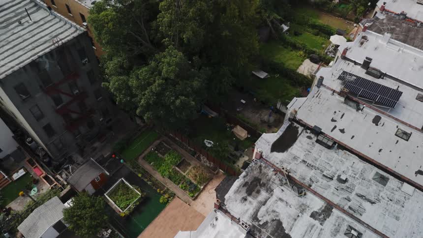 An aerial view of a row of houses with white roofs and backyards