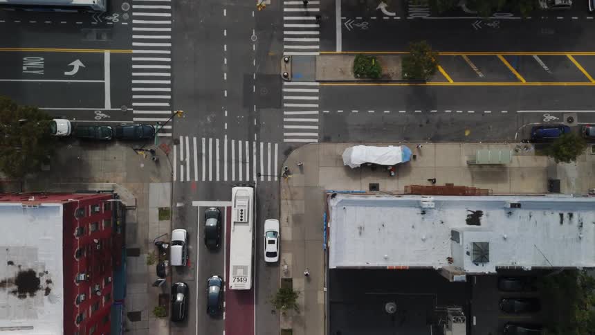 Pedestrians cross city streets as traffic moves on roads between buildings