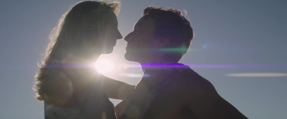 Woman and man kissing with sun reflection