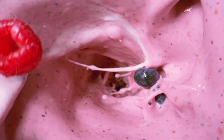 Fruits being tossed into yogurt and blended into a smoothie