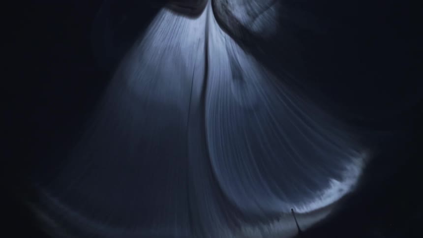 Whisps of white smoke flow down on a black background