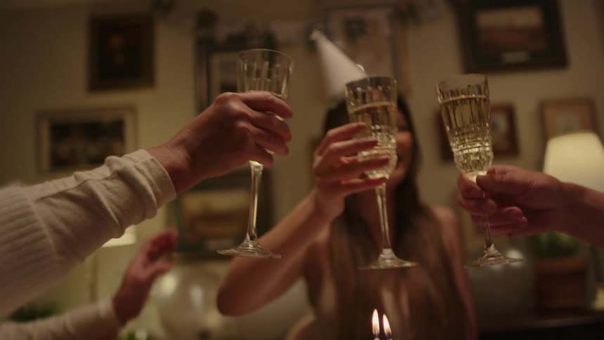 A woman with a hat toasting a glass with two other people in a celebratory tone