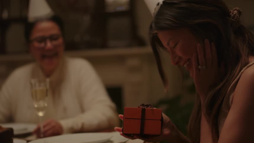 Happy womans receives a gift for her birthday at the dinning table