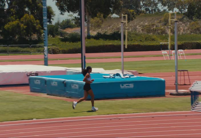 Woman running on an athletics track through the trees