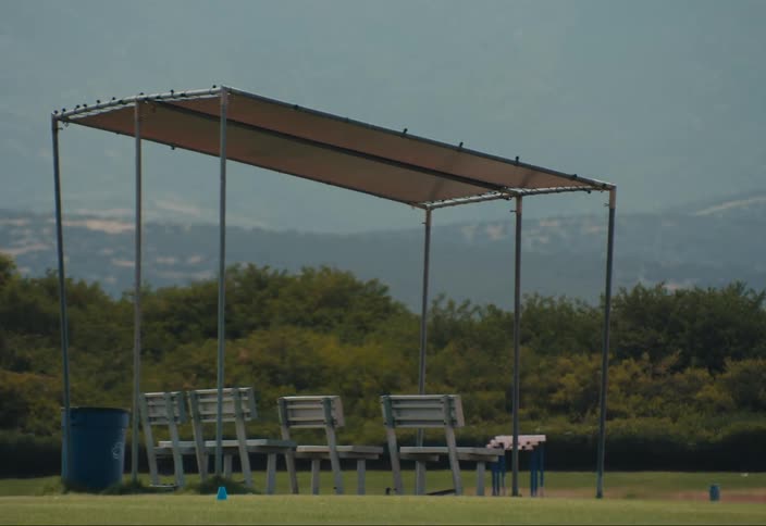 Chairs in a small shade tent in an open field on the lawn