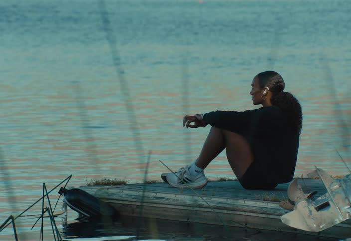 Woman wearing hearing aids sits on floating dock looking at the water