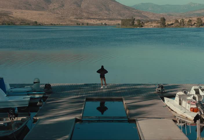 Woman stands on a dock looking out at a lake