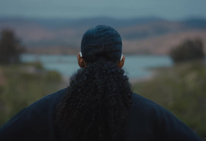 A woman gazes at the distant lake and mountains