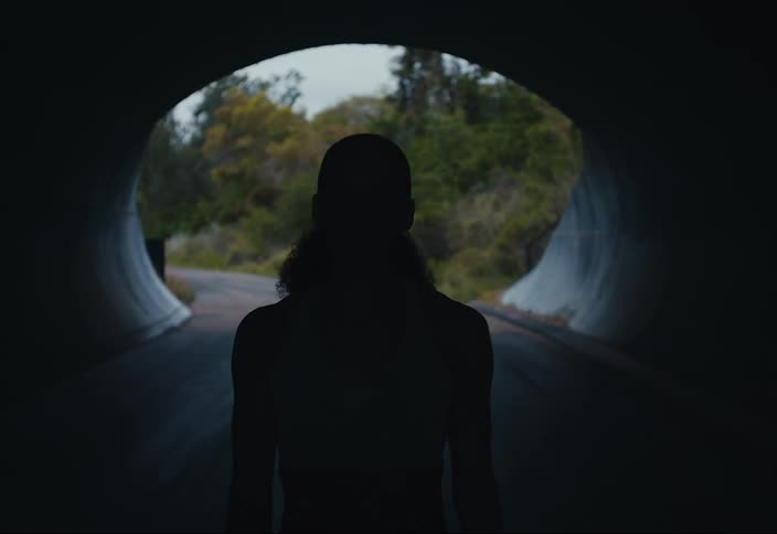 A woman walks through a tunnel