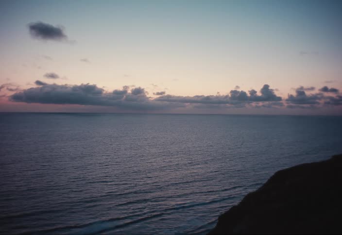 A large body of water with clouds in the sky at dusk