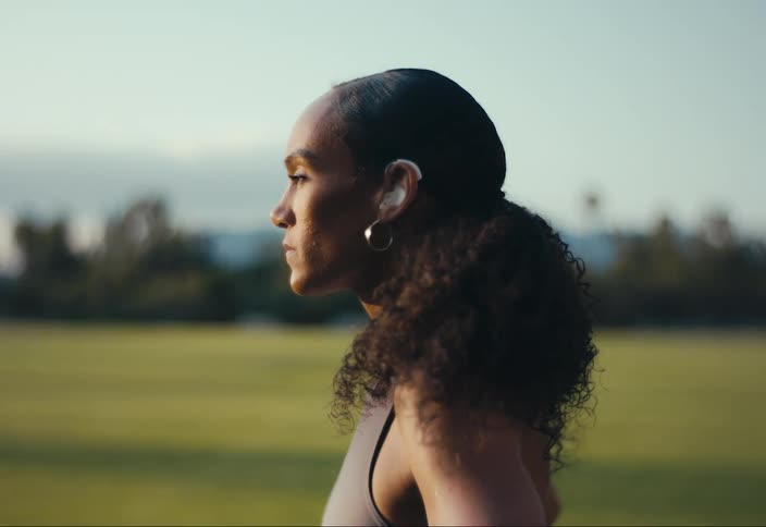 Woman standing in field wears a hearing aid
