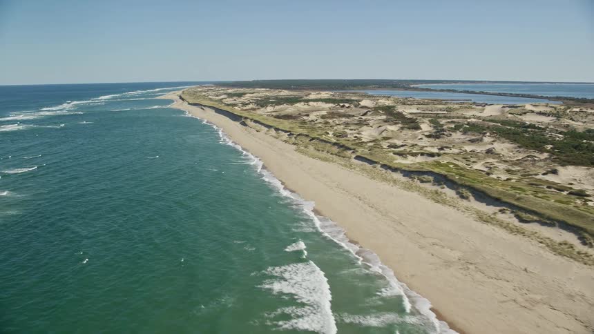An island with long lenght being hit by little waves from the sea