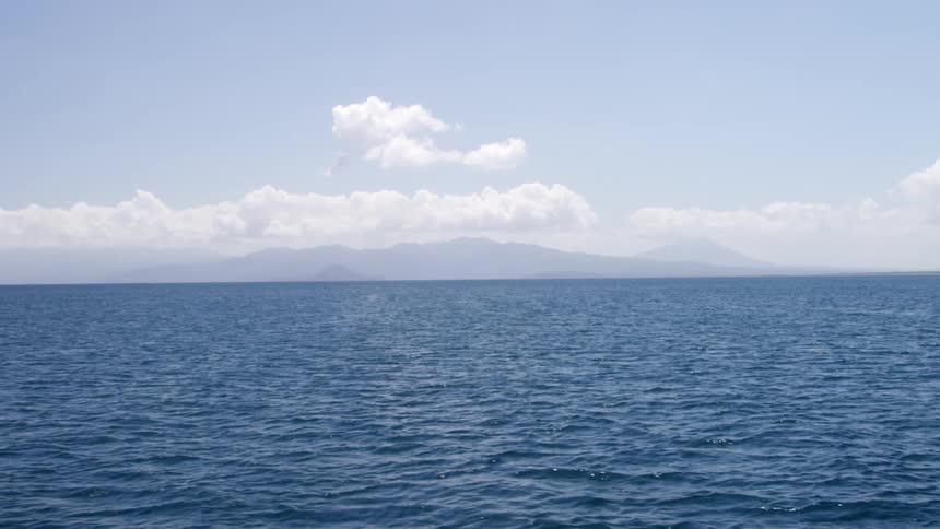 The blue water is rough with land barely visible in the distance