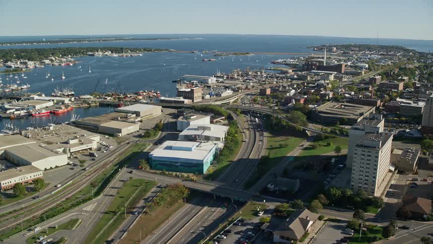 A city with tall buildings and several highways that is close to the sea