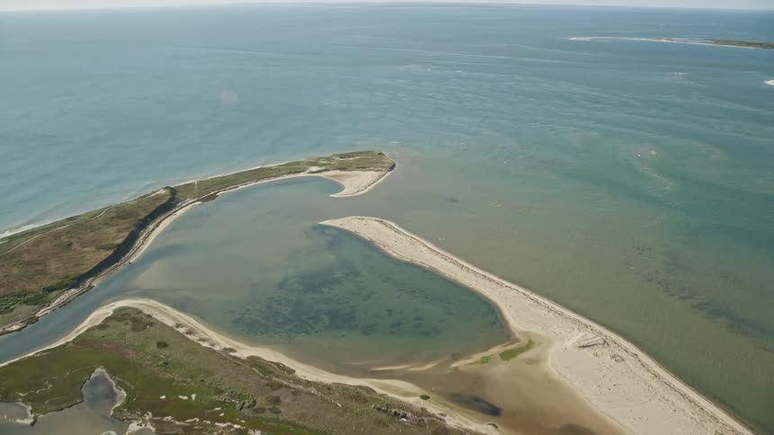 A river sitting and surrounded by green vegetation with the sea just close by separated by a beach from the river