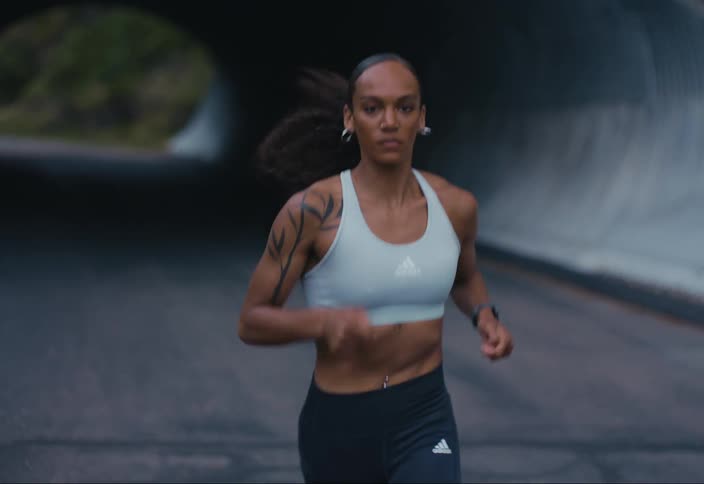 A woman runs along a road out of a tunnel