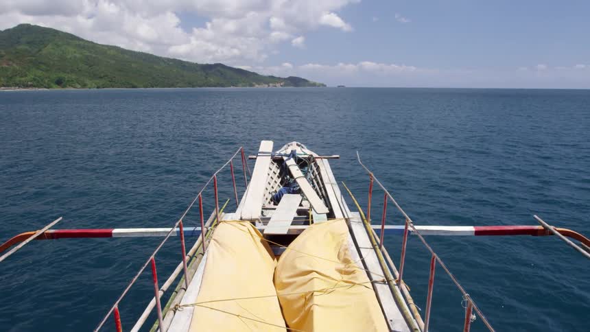 The boat is empty sailing towards the land ahead