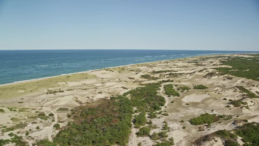 A region with a large sandy beach facing the blue sea that goes all the way to the horizon
