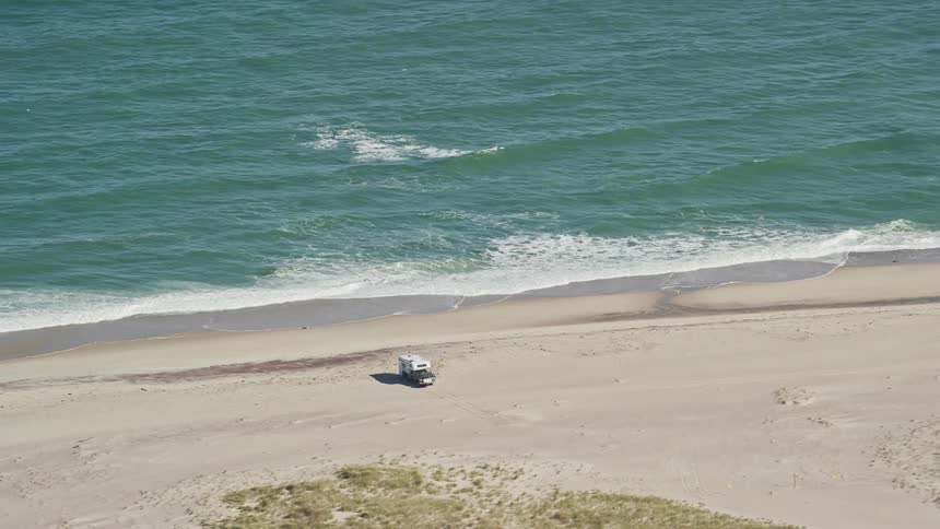 A small truck parked on the sand of a beach