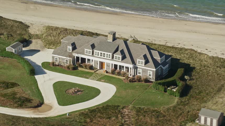 Large houses line the beach as surf rolls onto the sand