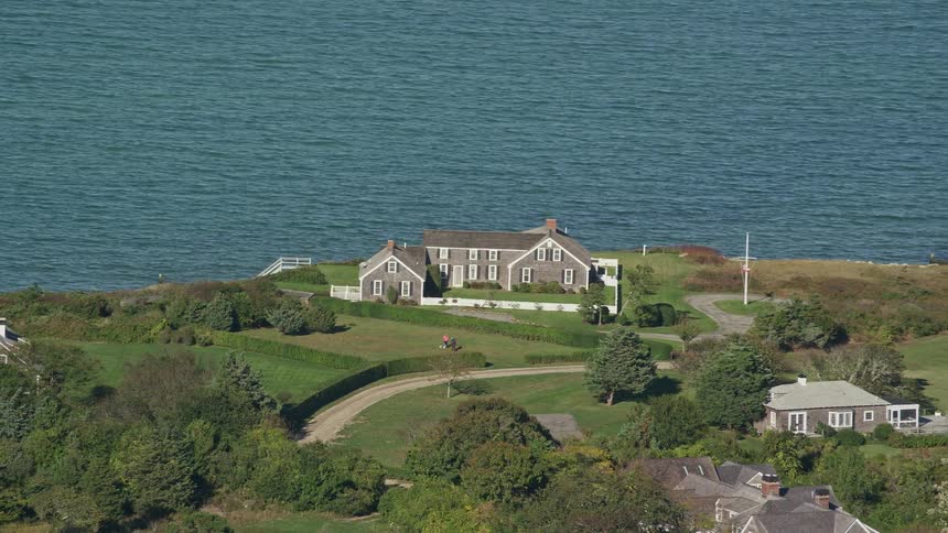 A large house on the seafront in a rural area with lots of grass and trees