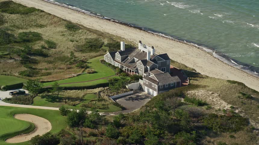 Few houses close to the beach surrounded by green grasses
