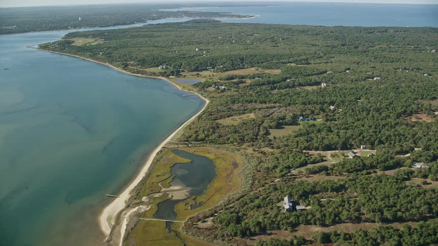 A large island with lots of forest and some houses facing the sea