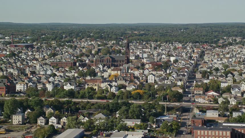 A city with low houses and a large church and a highway with several cars passing by