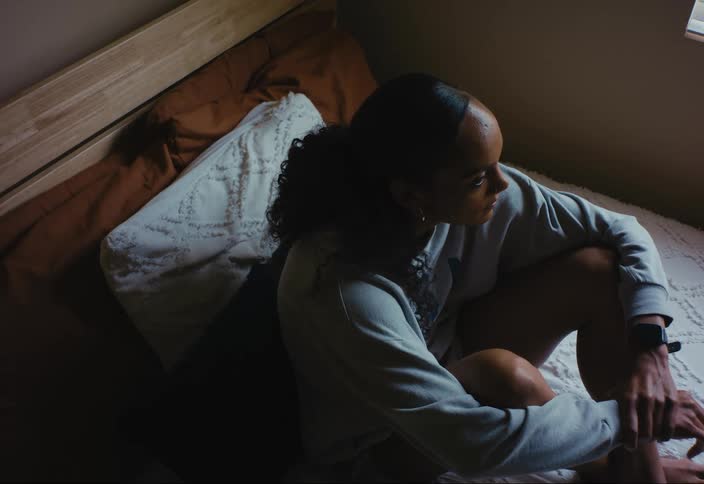 Woman sitting on a bed lost in thought