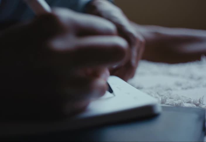 Close up of womans hands writing in notebook