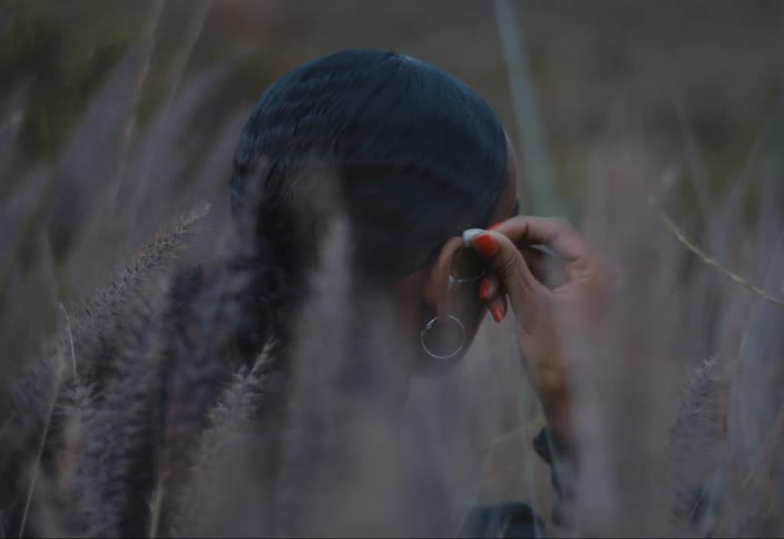 Woman sitting in a field of flowers putting on a hearing aid