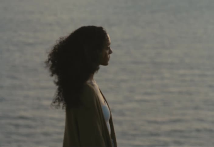 A woman is standing by the windy ocean