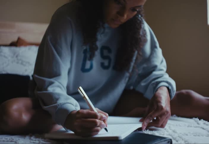 A woman writes in a notebook at home