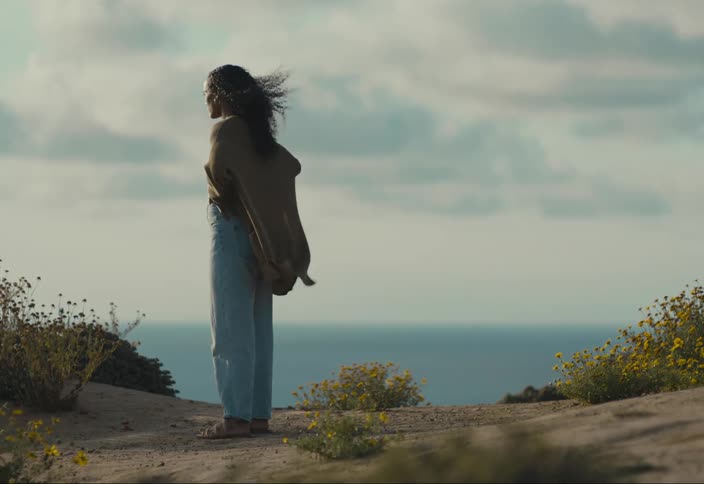 A woman walks to the edge of a cliff and observes the horizon