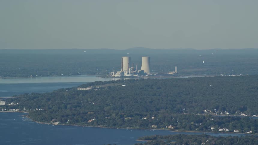 Traffic moves across a bridge with a nuclear power plant along the coast