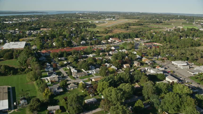 Traffic moves on the streets of a residential area with houses and apartments and a neighborhood school